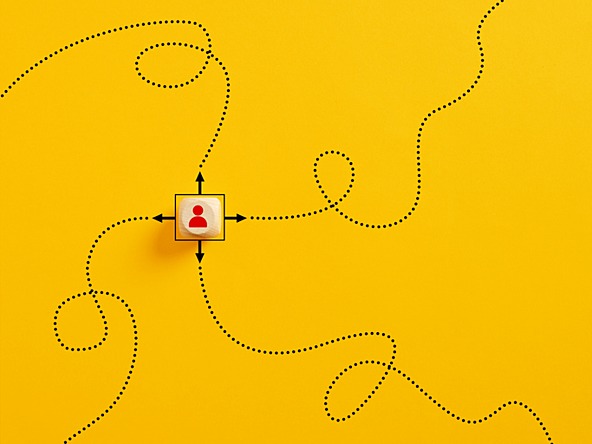wooden cube with silhouette of person and arrows pointing in four directions to dotted swirling lines